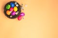 Colorful painted Easter Egg Nest with orange pastel colored background top view, Happy Easter Holliday concept background with