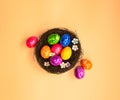 Colorful painted Easter Egg Nest with orange pastel colored background top view, Happy Easter Holliday concept background with