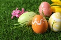Colorful painted Easter eggs and flowers on green grass, closeup. Royalty Free Stock Photo