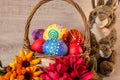 Easter eggs painted in a basket with flowers in lilac tones, and candles around on a wooden backgroundColorful painted Easter eggs