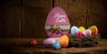 Colorful painted happy easter eggs in birds nest basket on rustic wooden old panorama background copy space Royalty Free Stock Photo