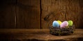 Colorful painted happy easter eggs in birds nest basket on rustic wooden old panorama background copy space Royalty Free Stock Photo