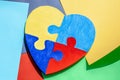 Colorful painted jigsaw puzzle heart on multicolored paper background. World autism awareness day, Autism spectrum Royalty Free Stock Photo