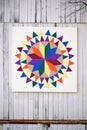 Colorful Painted Rainbow Quilt Block Hanging on White Barn