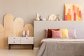 Colorful painting on grey bedhead of bed with cushions in bedroom interior with cabinet. Real photo Royalty Free Stock Photo
