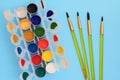 Colorful paints in jars on a blue background near the brushes. Color palette. Concept-creativity and school theme