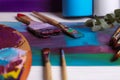 Colorful paints, wooden artist`s palette and different brushes on white table, closeup Royalty Free Stock Photo