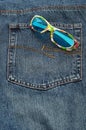 A colorful pair of sunglasses in the back pocket of a denim