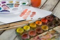 Colorful palette, paintbrushes and paper on wooden surface