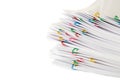 Colorful paper clip with pile of overload white paperwork isolated on white