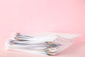 Colorful paper clip with pile of overload white paperwork on pink