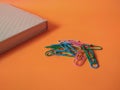 Colorful paper clips isolated on orange background