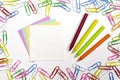 Colorful paper clips, note papers and wax pencils in the centre of composition isolated on white Royalty Free Stock Photo