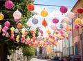 Colorful paper lanterns of different sizes hang on ropes above the street, against the backdrop of buildings. Street Royalty Free Stock Photo