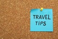 Colorful paper note with phrase Travel Tips pinned to cork board, closeup. Space for text Royalty Free Stock Photo