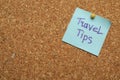 Colorful paper note with phrase Travel Tips pinned to cork board, closeup. Space for text Royalty Free Stock Photo