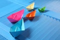 Colorful paper ships on blue wooden background Royalty Free Stock Photo