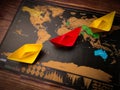 Colorful paper ships on the world map placed on a wooden table Royalty Free Stock Photo