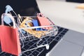 Colorful paper shopping bag in trolley on laptop. Customer can buy everything from office or home