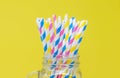 Colorful paper straws in a glass mason jar. with a yellow background. Closeup with a shallow depth of field Royalty Free Stock Photo