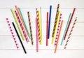 Colorful paper straws on white wooden background.
