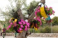 Colorful parrot decorations, hanging on the tree, made with car tires and pink petunias Royalty Free Stock Photo