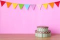 Colorful party flags hanging on pink background and gift box on Royalty Free Stock Photo
