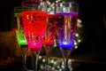 Colorful party glasses, red, blue and green, filled with champagne, cava or prosecco, on a dark and black background.