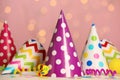 Colorful party hats and festive items on white table against pink background with blurred lights Royalty Free Stock Photo