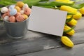 Colorful easter candy eggs with yellow tulips and empty greeting card on wooden table Royalty Free Stock Photo