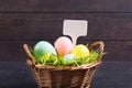 Colorful pastel Easter eggs with green natural grass in basket with white label. Copy space Royalty Free Stock Photo