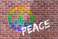 Colorful Peace Sign And White Peace Lettering Over Red Brick Wall In Background