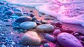 Colorful pebbles on a beach with foamy waves during sunset Royalty Free Stock Photo