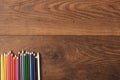Colorful pencils on the brown wooden table background. Frame of colored pencils over wood with free space for text Royalty Free Stock Photo