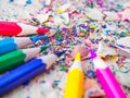 Colorful pencils with colorful pencil shavings on wooden background. Royalty Free Stock Photo