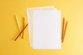 Colorful pencils and empty white papers . Empty place for text or drawing on the yellow background, top view Royalty Free Stock Photo