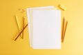 Colorful pencils, eraser and empty white papers . Empty place for text or drawing on the yellow background, top view Royalty Free Stock Photo