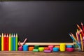 Colorful pencils, erasers, and markers neatly arranged in front of a blank blackboard, ready for a creative classroom session.
