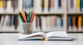 Colorful Pencils in a Holder Next to an Open Notebook in a Library Setting Royalty Free Stock Photo