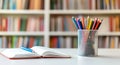 Colorful Pencils in a Holder Next to an Open Notebook in a Library Setting. Royalty Free Stock Photo