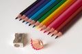 Colorful pencils with pencil sharpener on a sheet of white paperboard Royalty Free Stock Photo