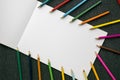 Colorful pencils on white paper copy space over wooden textured background. Royalty Free Stock Photo