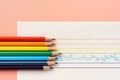 Colorful pencils on white paper and multicolored lines on yellow background Royalty Free Stock Photo