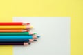 Colorful pencils on white paper on yellow background Royalty Free Stock Photo