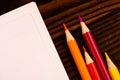 Colorful pencils and white sheets of paper on a wooden table Royalty Free Stock Photo