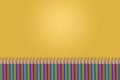 Colorful pencils on yellow gradient background