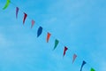 Colorful pennants hanging with rope against blue sky.