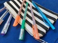 Colorful pens on old pen case at blue surface