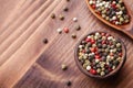 Colorful peppercorns in rustic bowl on wooden table top view.