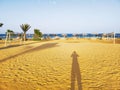 Colorful picturesque beach scenery with golden yellow sand, human shadow, palms, football and volleyball field Royalty Free Stock Photo